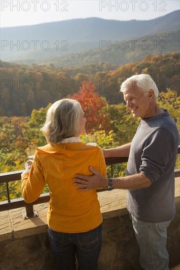 Older Caucasian couple enjoying wine and scenic view