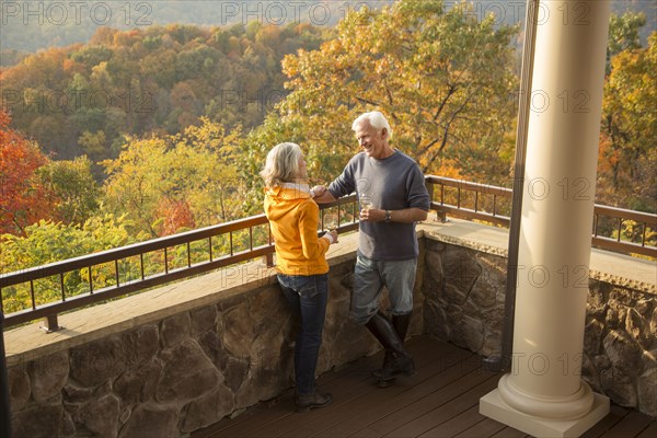 Older Caucasian couple enjoying wine and scenic view