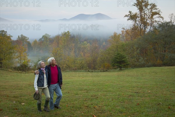 Older Caucasian couple walking in field