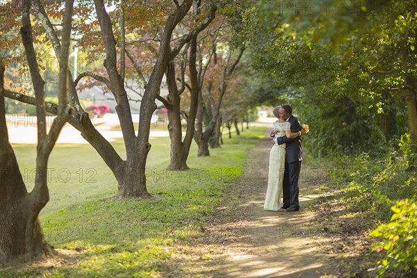 Black couple hugging on path in park