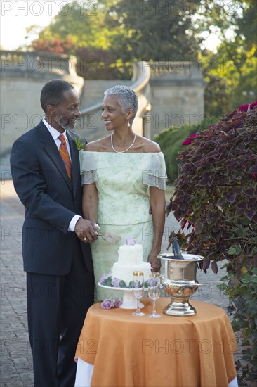 Black couple cutting wedding cake