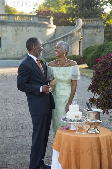 Black couple laughing near wedding cake