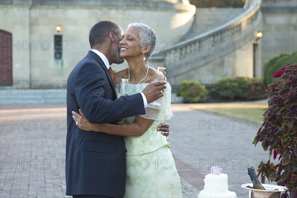 Black couple hugging near wedding cake