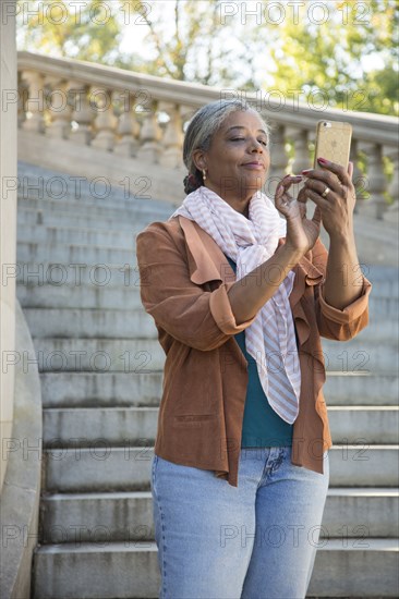 Black woman on stone staircase texting on cell phone