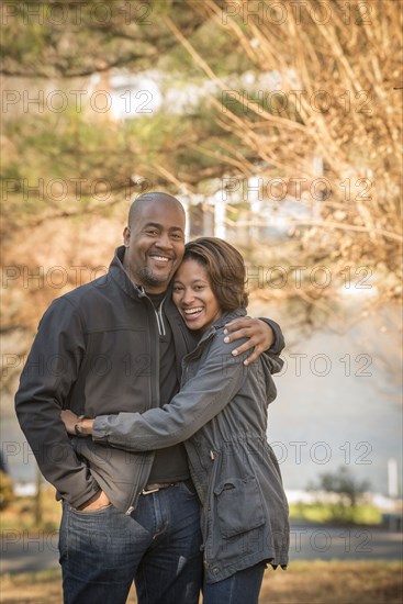 Portrait of smiling Mixed Race father and daughter hugging outdoors
