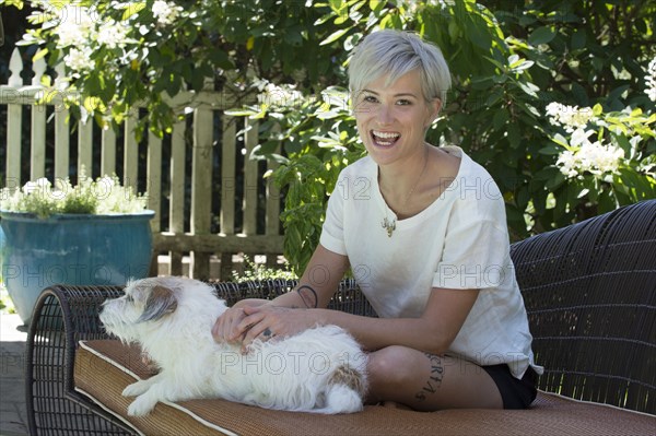 Smiling Caucasian woman petting dog on sofa outdoors