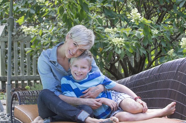Caucasian woman hugging son on sofa outdoors