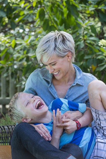 Caucasian woman tickling son outdoors