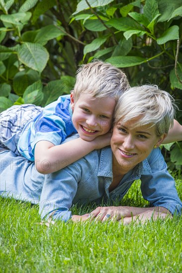 Caucasian boy laying on back of mother in grass