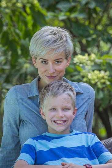 Caucasian boy leaning on mother outdoors