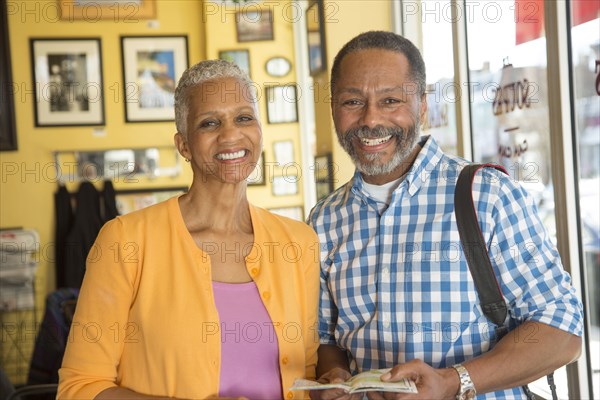 Portrait of Mixed Race couple holding map in coffee shop