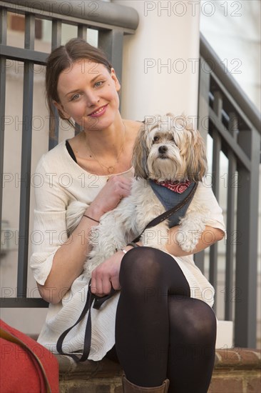 Portrait of Caucasian woman sitting on stoop holding dog