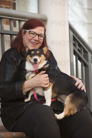 Portrait of Caucasian woman sitting on stoop holding dog