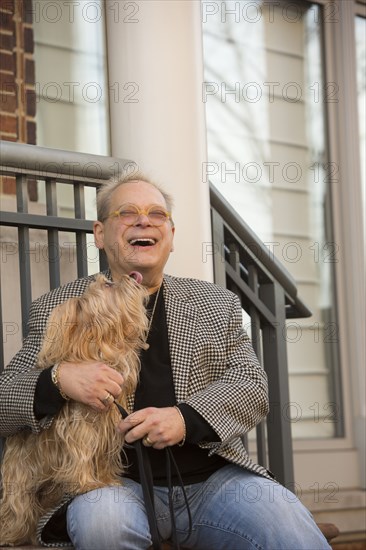 Portrait of Caucasian man sitting on stoop holding dog