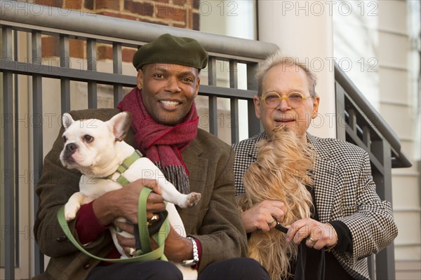 Portrait of men sitting on stoop holding dogs