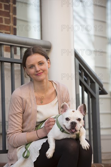 Portrait of Caucasian woman sitting on stoop holding dog