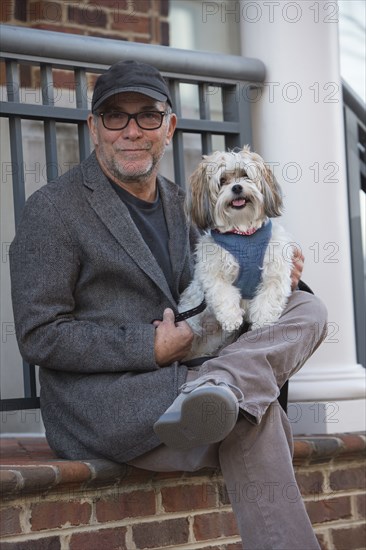 Portrait of Caucasian man sitting on stoop posing with dog