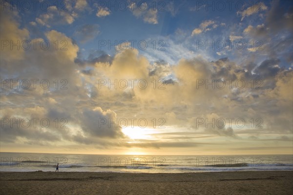 Distant man walking on beach at sunset