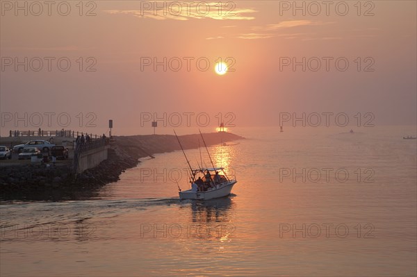 People on boat and at waterfront at sunset