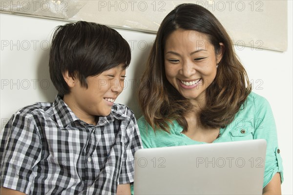 Smiling Asian mother and son using laptop