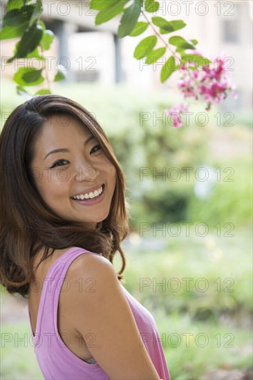 Portrait of smiling Asian woman outdoors near flowers
