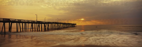 Ocean waves under pier at sunset