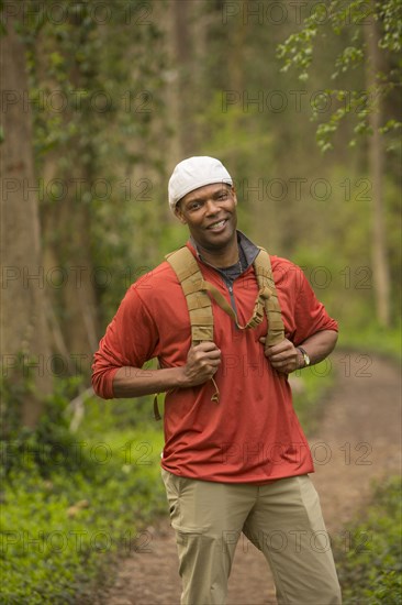 African American man standing on path in forest carrying backpack