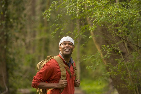 African American man standing in forest carrying backpack