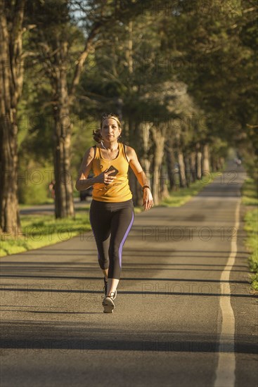 Caucasian woman running on path listening to cell phone