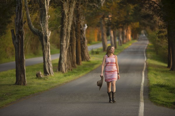 Caucasian woman walking on path holding cowboy hat