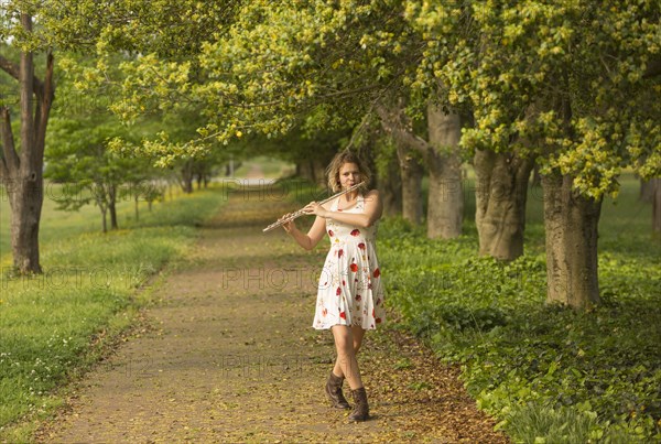 Caucasian teenage girl playing flute in park