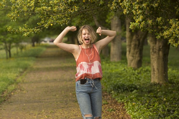 Caucasian girl dancing in park listening to earbuds