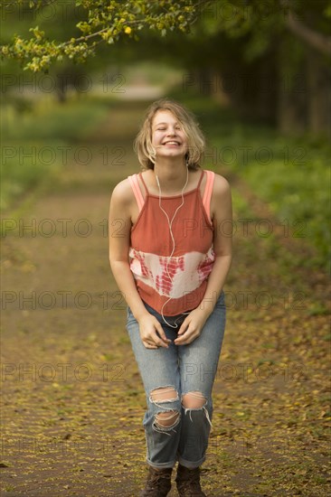 Caucasian girl dancing in park listening to earbuds