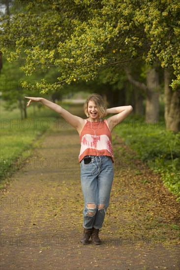 Caucasian girl dancing in park listening to earbuds