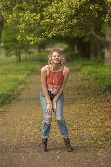 Caucasian girl dancing in park listening to earbuds