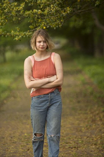 Caucasian teenage girl with arms crossed in park