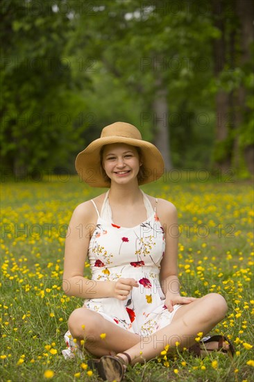 Caucasian teenage girl sitting in field of flowers