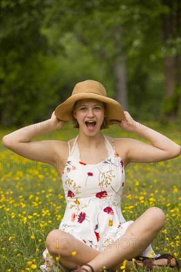 Surprised Caucasian teenage girl sitting in field of flowers