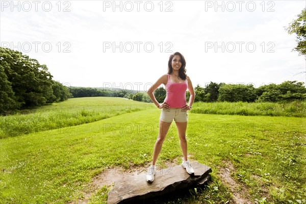 Hispanic woman standing on rock in field