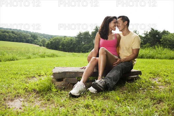 Hispanic woman sitting on rock in field