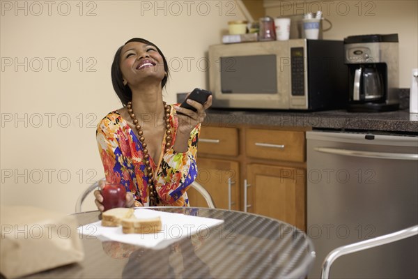 Mixed race businesswoman eating lunch in break room