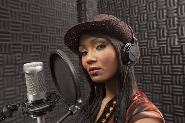 Mixed race woman singing in recording studio