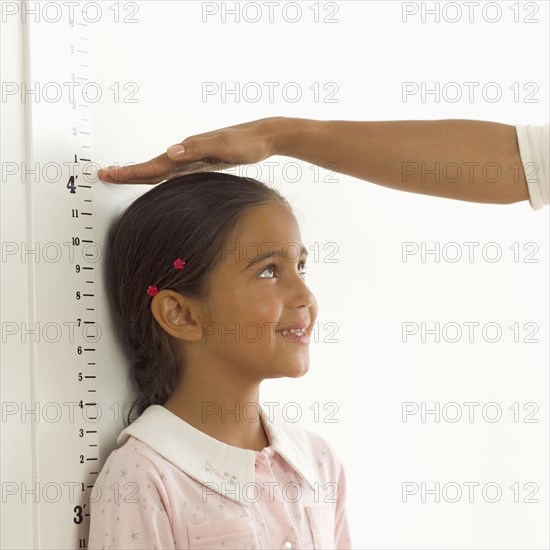 Woman measuring girl's height