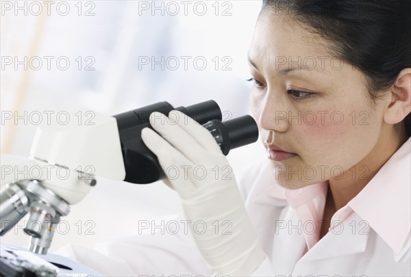 Woman in lab looking through microscope