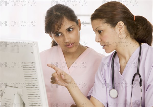 Two nurses talking in front of computer