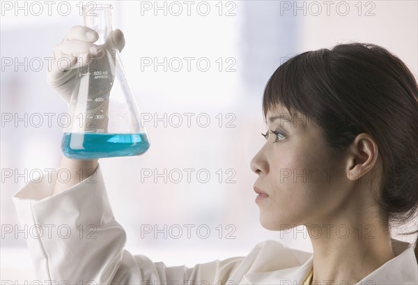 Woman in lab looking at liquid in beaker