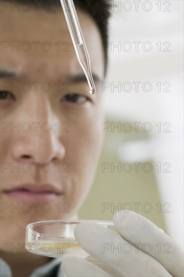 Close up of man with eye dropper and petri dish