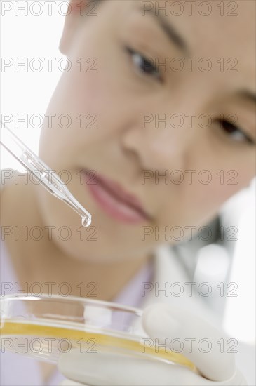 Close up of woman with eye dropper and petri dish