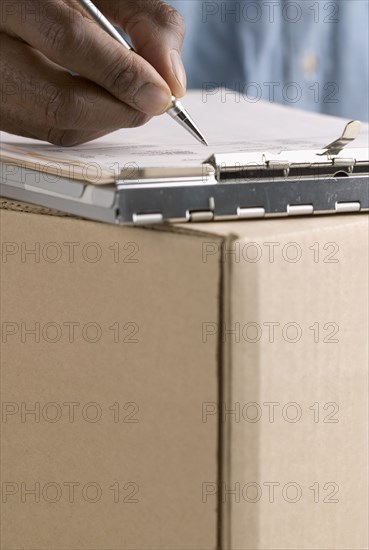 Close up of hand writing on clipboard