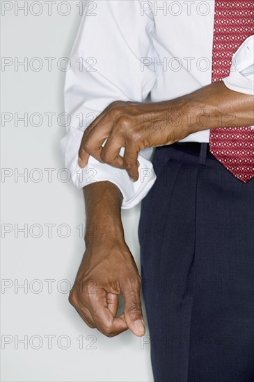 Midsection of businessman rolling up sleeve